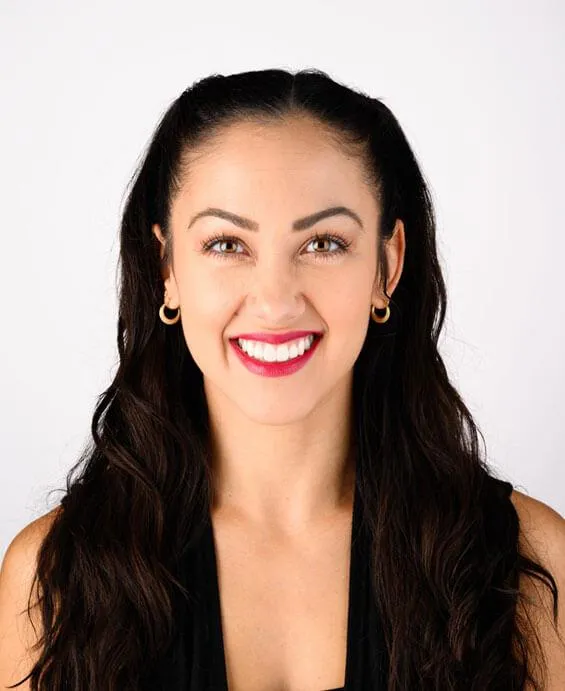 Professional headshot of smiling woman with long dark hair against white background for dental practice.
