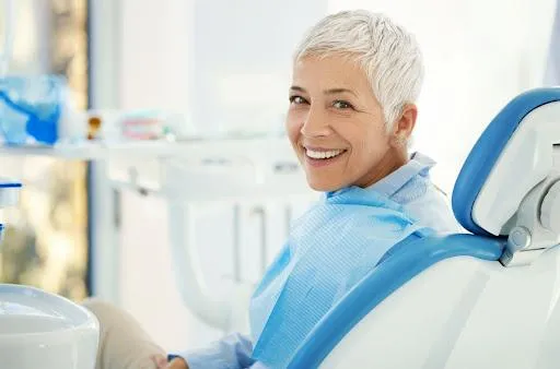 Smiling mature patient in blue bib sitting in dental chair at Vibe Dentistry Spring clinic.
